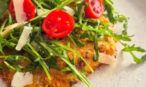 Knuspriges paniertes Hähnchen mit Rucola, Kirschtomaten und Parmesan.