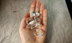 Kilka gładkich kryształów górskich w dłoni, symbolizujących ich magiczne właściwości i moc oczyszczania.