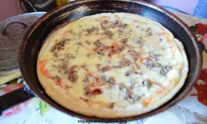 Pizza à la poêle, garnie de viande hachée et de fromage fondant, prête à être dégustée.