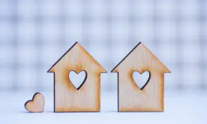 Due casette di legno con cuori intagliati, una più piccola accanto. Simboleggiano la casa e l'amore, ma anche i potenziali conflitti legati ai lavori senza consenso comproprietari.
