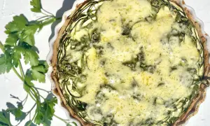 Eine köstliche Zucchini-Quiche mit goldbraunem Teig und einer cremigen Füllung, garniert mit frischer Petersilie.