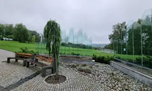 Ławki i ozdobne drzewko w Ustroniu, idealne na deszczowe atrakcje. Szklane panele tworzą nowoczesną instalację.