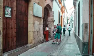 Un grupo de turistas pasea por una calle estrecha y empedrada del quartier juif de Cordoue, admirando la arquitectura antigua.