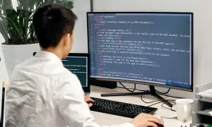 Programista uczy się podstaw Docker, pisząc kod HTML na monitorze.