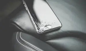 Uszkodzony ekran telefonu leżący na skórzanym siedzeniu.