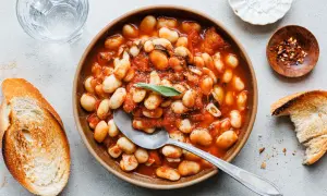 Herzhafte weiße Bohnen in Tomatensoße, garniert mit Salbei. Perfekt für einfache Salbei Rezepte, serviert mit geröstetem Brot.