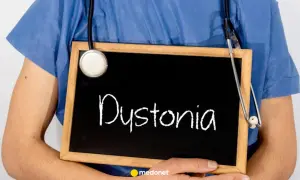 Lekarz w niebieskiej koszuli trzyma tabliczkę z napisem "Dystonia". Stetoskop zwisa na jego ramieniu.