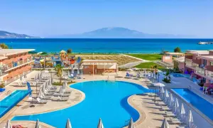 Słoneczny dzień w Alykanas Beach Hotel. Baseny, zjeżdżalnie wodne i leżaki czekają na gości. W tle błękitne morze i góry.