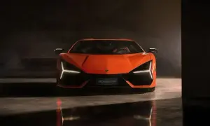 Pomarańczowy Lamborghini Revuelto z ostrymi światłami LED, odbijający się w mokrej podłodze.