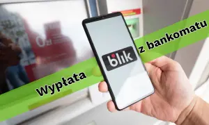 Dłoń trzyma smartfon z logo Blik przed bankomatem. Można w ten sposób wypłacić pieniądze.