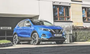 Niebieski Nissan Qashqai 1 parkuje przed garażem.