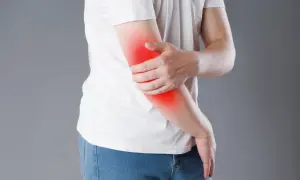 Person håller om sin arm där det lyser rött, vilket indikerar att det gör ont i underarmen.