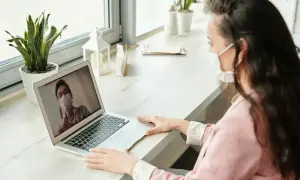 Kobieta na wideokonferencji z lekarzem, który wyjaśnia, ile trzeba przepracować żeby iść na chorobowe.