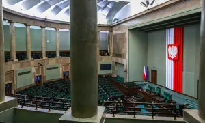 Sala sejmowa z rzędem zielonych foteli. Na ścianie godło Polski i flagi. Kto to lobbysta? Ktoś, kto próbuje wpływać na decyzje.