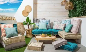 Acogedora zona chill out interior con cojines coloridos, suelo de césped artificial y luces de estilo bohemio.