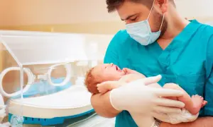 Lekarz w maseczce i rękawiczkach trzyma noworodka, troskliwa neonatologia.
