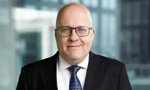 Mikael Staffas, en man med glasögon och kostym, ler mot kameran.