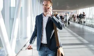 Mężczyzna w marynarce rozmawia przez telefon, ciągnąc walizkę. Może to być związane z podróżą służbową, o której mowa w art. 21 ust. 1 pkt 152 ustawy o podatku dochodowym.