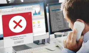 Błąd na ekranie komputera. Mężczyzna rozmawia przez telefon, próbując dowiedzieć się, jak usunąć się z administratora strony na FB.