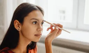 Dziewczyna aplikuje hennę do brwi. Różne rodzaje henny do brwi pozwalają na uzyskanie naturalnego efektu.