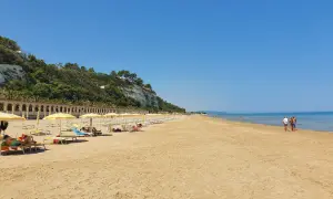 Spiaggia di ponente Rodi Garganico: sabbia dorata, ombrelloni gialli e un mare azzurro sotto un cielo limpido.