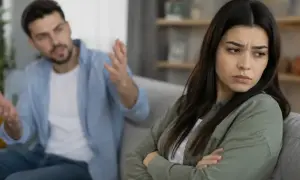 Zaborcza osoba krzyczy na partnerkę, która zamyka się w sobie, czując się przytłoczona jego kontrolą.