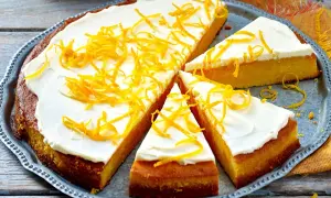Ein saftiger, gesunder Kuchen mit weißem Zuckerguss und orangen Zesten verziert, auf einem silbernen Blech.
