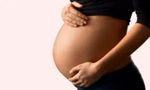 Schwanger und besorgt wegen eines Bandscheibenvorfalls? Die Hände einer Frau stützen sanft ihren runden Bauch.