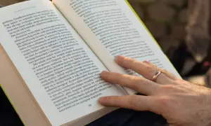 Dłoń z obrączką na palcu, która delikatnie dotyka strony książki. Tekst na stronie opisuje zjawisko wallenrodyzmu i jego wpływ na samopoczucie.
