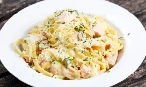 Pyszne fettuccine z łososiem w kremowym sosie, posypane parmezanem i świeżym koperkiem. Idealne danie dla miłośników ryb.