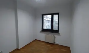 Puste, białe pomieszczenie z drewnianą podłogą i oknem. Zastanawiasz się, ile trwa malowanie pokoju?