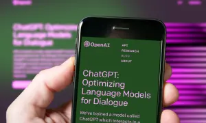 Dłoń trzyma smartfon z otwartą stroną OpenAI, prezentującą ChatGPT: Optymalizację modeli językowych do dialogu.