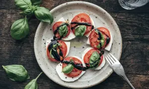 Tomate-Mozzarella-Salat mit frischem Basilikum und Balsamico-Glasur auf einem rustikalen Teller.