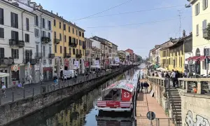 En båt på Navigli i Milano, omgiven av färgglada byggnader och folk som promenerar längs kanalen.