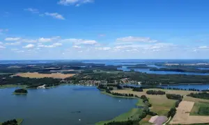 Krajobraz z lotu ptaka, gdzie widać liczne jeziora i lasy, tworzące malowniczą krainę tysiąca jezior.