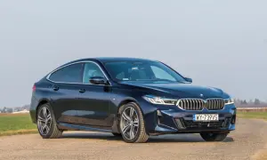 Eleganckie, granatowe BMW 640i na tle pól i błękitnego nieba.