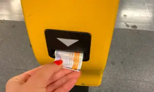 Dłoń z czerwonym lakierem wkłada bilet do żółtego automatu. To część podróży komunikacją miejską w Pradze.