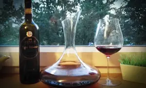 Butelka wina Egri Bikavér, karafka i kieliszek z czerwonym winem. Właściwości tego węgierskiego trunku są cenione przez koneserów.