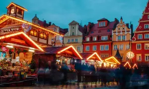 Bunte Häuser und beleuchtete Stände auf dem Wroclaw Weihnachtsmarkt. Menschen schlendern durch die festliche Atmosphäre.