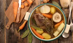 Un bol fumant de pot-au-feu, avec viande, carottes, pommes de terre, oignon et os à moelle. Une recette réconfortante.