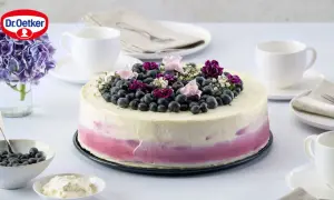 Eine wunderschöne Heidelbeertorte mit Joghurt-Frosting, garniert mit frischen Beeren und Blüten.