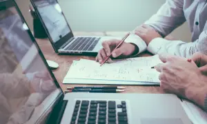 Dwie osoby pracują nad dokumentem, analizując dane i planując strategię. To kluczowy etap, by dowiedzieć się, jak napisać biznesplan.