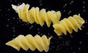 Dwa makarony fusilli gotujące się w wodzie, otoczone bąbelkami. Idealny przykład, jak ugotować makaron.