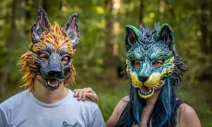 Dwie osoby w maskach wilków, symbolizujące tożsamość therian. Jedna w odcieniach pomarańczu, druga w zieleni i błękicie.