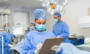 Zespół medyczny przygotowuje się do operacji. Pielęgniarka notuje informacje, być może dotyczące tego, ile trwa operacja usunięcia nerwiaka.