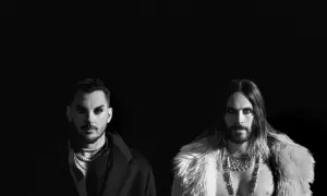 Jared Leto i Shannon Leto z 30 Seconds to Mars na czarno-białym zdjęciu. Jared w futrzanym płaszczu, Shannon w eleganckim płaszczu.