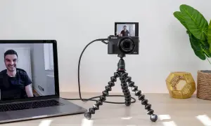 Ustawienie do streamingu: aparat Canon G7X na statywie Joby, podłączony do laptopa. Widoczny uśmiechnięty mężczyzna na ekranie. Idealne do streamingu z użyciem **EOS Utility**.