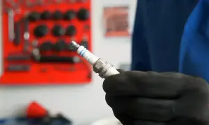 Main tenue une bougie d'allumage neuve, prête à être installée. Savoir quand changer les bougies d'allumage est essentiel pour le bon fonctionnement de votre moteur.