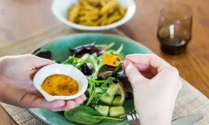 Mani aggiungono curcuma a un'insalata, sfruttando i curcuma e pepe nero benefici per un pasto sano.