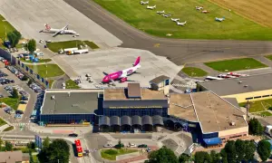 Lotnisko Wrocław na żywo: różowy samolot Wizz Air i mniejsze maszyny na płycie. Widać terminal i parkingi.